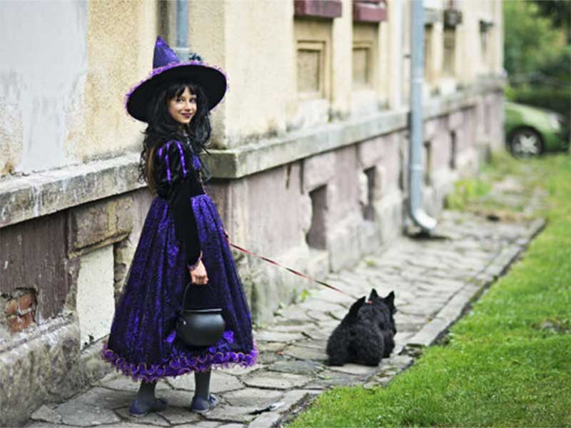 A woman dresses up as a witch walking her dog